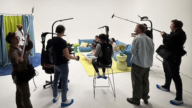 People filming a podcast or interview in a modern studio with colourful decor and recording equipment.